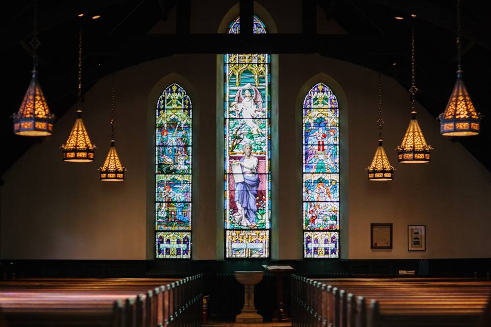 The chapel at rest &mdash; stained glass, lantern light, and quiet pews